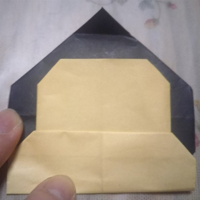 顔の部分(ベージュの折り紙)を１度開いて、下の２つの角を図のように折り、 再度、元に戻すと図のように顔の輪郭が出来上がります。