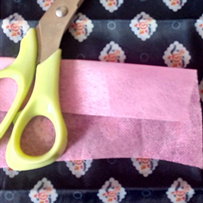 不織布の端を3センチ位折り返して筋をつけ、ハサミで切り、リボン状にします。